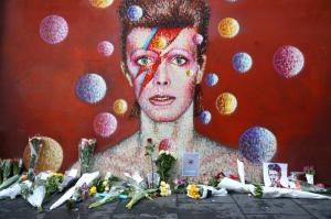 LONDON, ENGLAND - JANUARY 11: Flowers are laid beneath a mural of David Bowie in Brixton on January 11, 2016 in London, England. British music and fashion icon David Bowie died earlier today at the age of 69 after a battle with cancer.  (Photo by Carl Court/Getty Images)